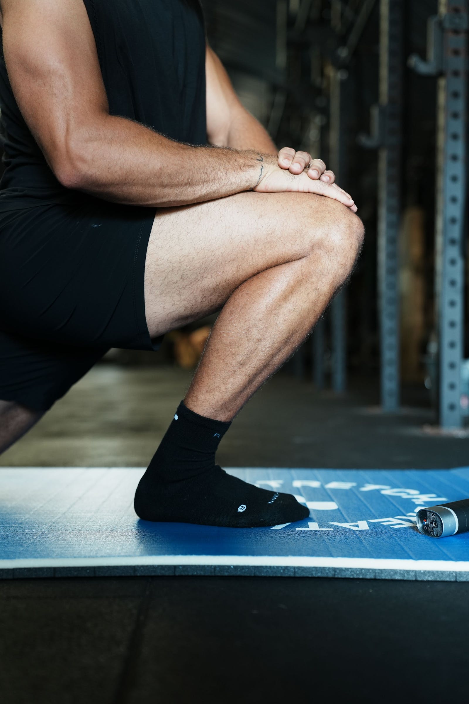 Close-up of an athlete's ankle and calf in a deep squat on a mat, knee traveling forward over the toes