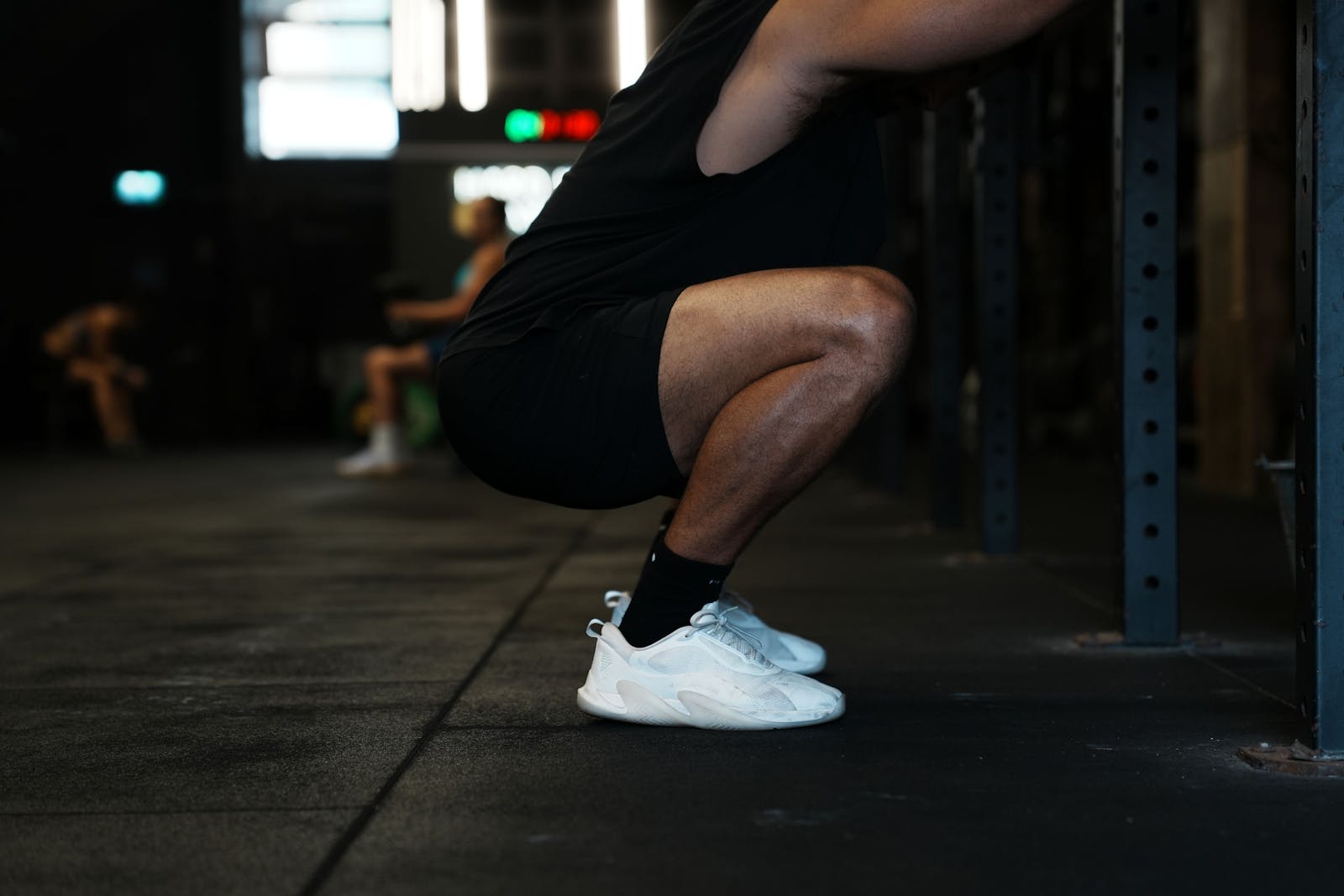 Athlete holding a deep bodyweight squat in a gym with heels flat and hip crease below the knee