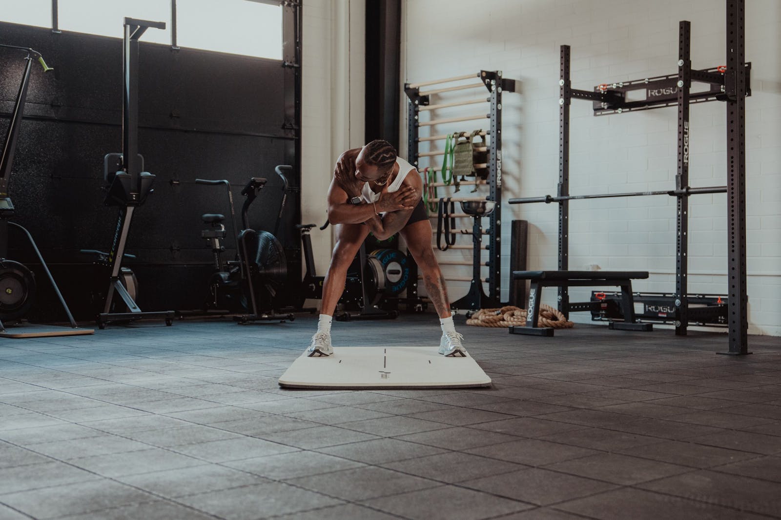 Athlete moving through a bodyweight squat on a mat, working full range of motion in a gym