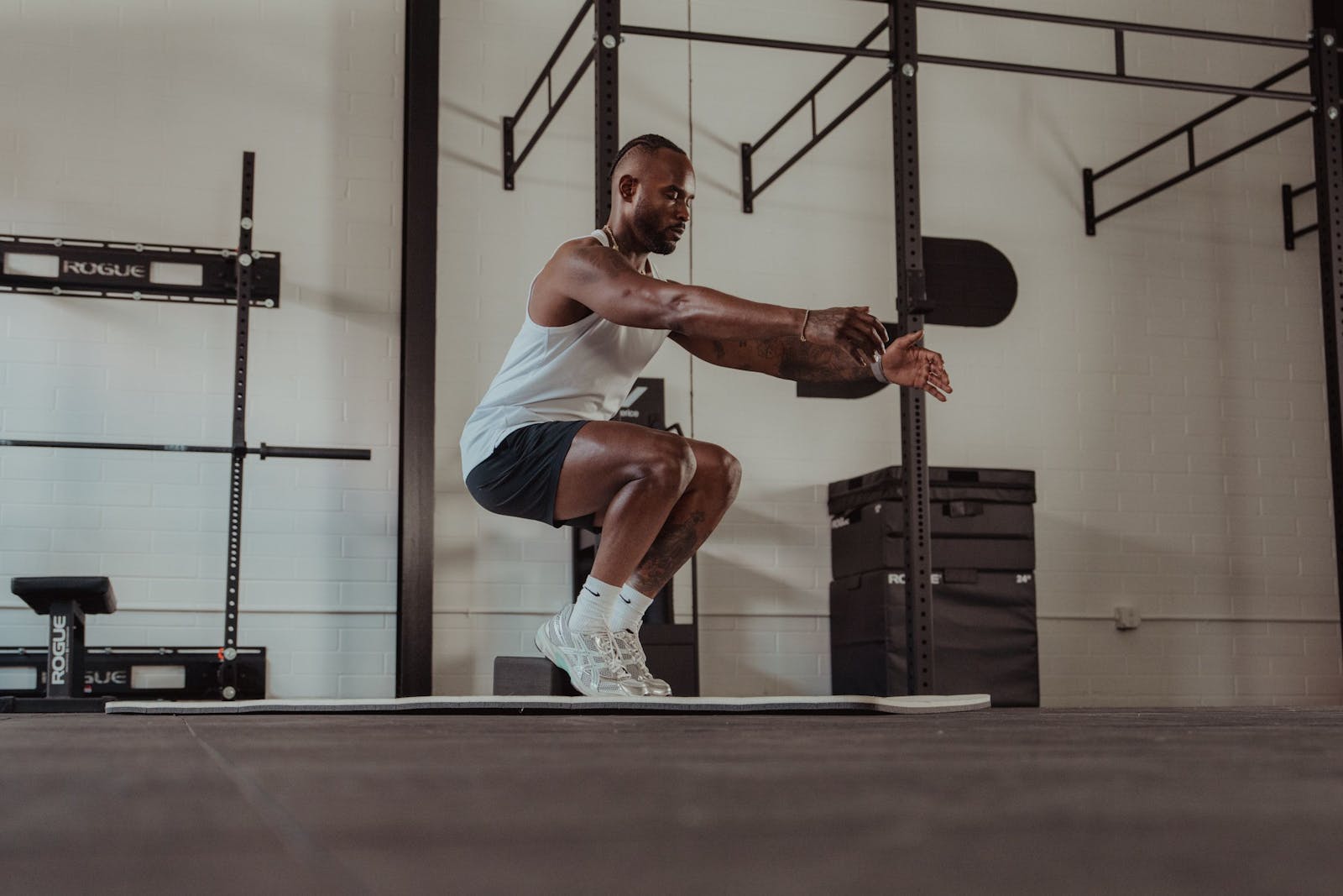 Athlete moving through a bodyweight squat on a gym mat