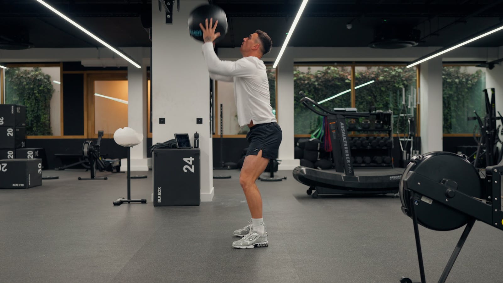 HYROX athlete throwing a wall ball toward the overhead target in a gym